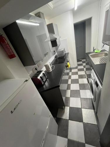 a kitchen with white cabinets and a checkered floor at Heath lodge in Newcastle under Lyme