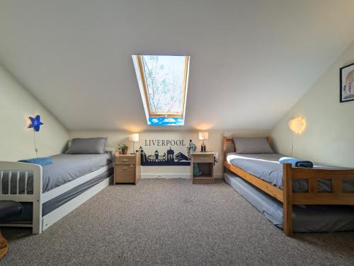 une chambre mansardée avec deux lits et une lucarne dans l'établissement Large 3-bedrooms House Near Centre Free Parking, à Liverpool