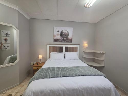 ポロクワネにあるGuest House On Marshallの大きな白いベッドと鏡のある寝室