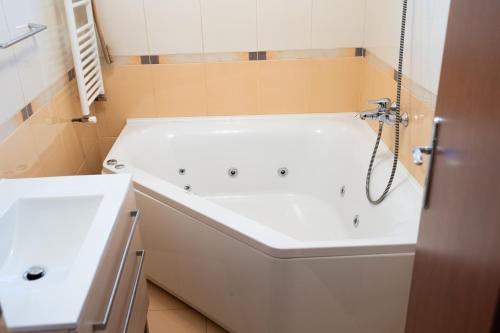 VulcanにあるChris Apartの白い浴槽と洗面台のあるバスルーム