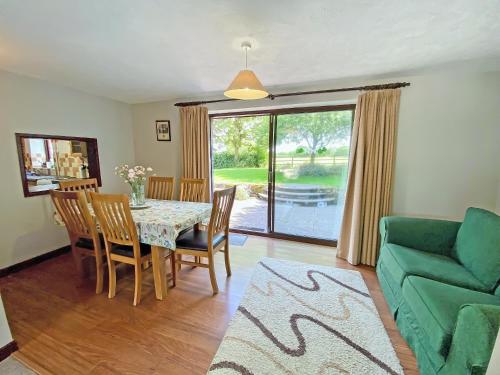 a dining room with a table and a green couch at Fox Cottage - E4510 in Chipping Sodbury