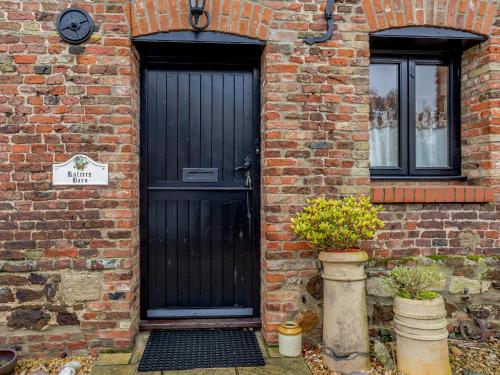 a black door on the side of a brick building at Rafters Barn - E2064A in Runcton Holme