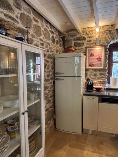 a kitchen with a refrigerator and a stone wall at Dreamy Cottage in Ayiá
