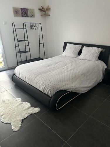 a bedroom with a bed with a white comforter and a rug at Appartement cosy in Montier-en-Der