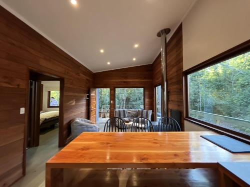 Zimmer mit Holzwänden, einem Tisch und Stühlen in der Unterkunft Cabaña Roble - BBQ Home Office Washer Wood Hot Tub in Huiscapi