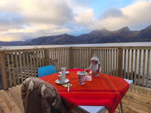 einen Tisch mit einem roten Tischtuch auf dem Deck in der Unterkunft Midnight-sun and Northern-lights house by ocean in Vestvågøya