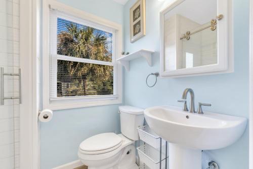 a bathroom with a toilet and a sink and a window at CM4005: 4005 Cameron Blvd. in Isle of Palms