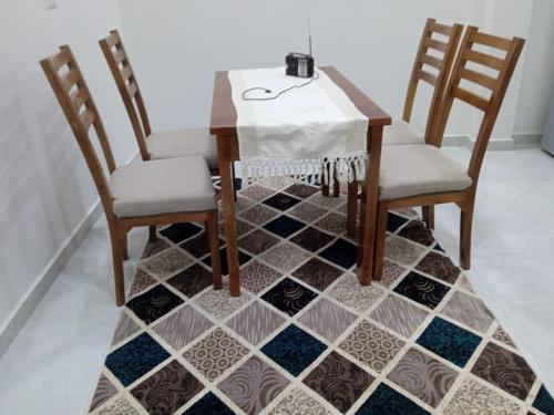 Al Aqālitahにあるmariam Gardenのダイニングテーブル、椅子2脚、タイル張りの床