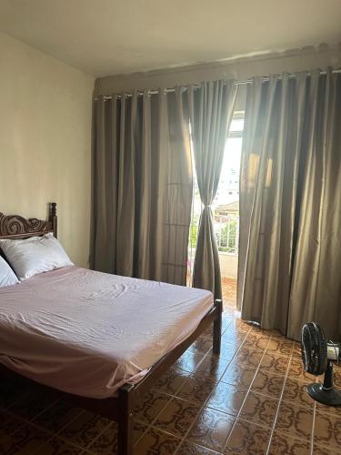 Un dormitorio con una cama y una ventana grande en Edifício solar de Piuma, en Piúma