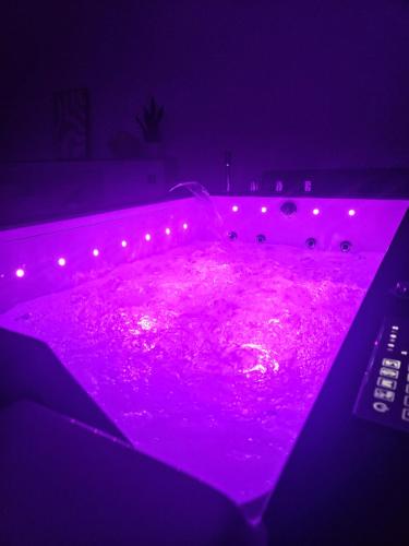 a purple bathtub with pink lights in a room at La suite Cherbourgeoise in Cherbourg en Cotentin