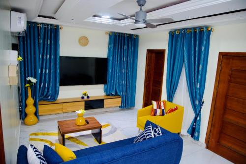 a living room with a blue couch and a tv at GreyCity Apartments in Accra