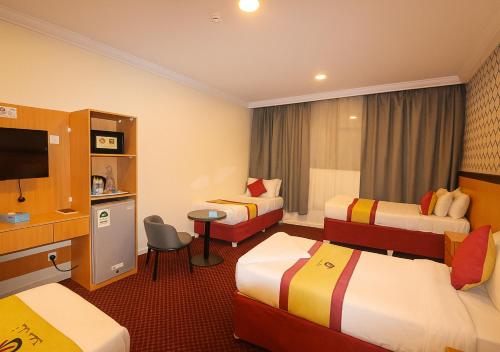 a hotel room with three beds and a television at فندق رفاق مكة in Makkah