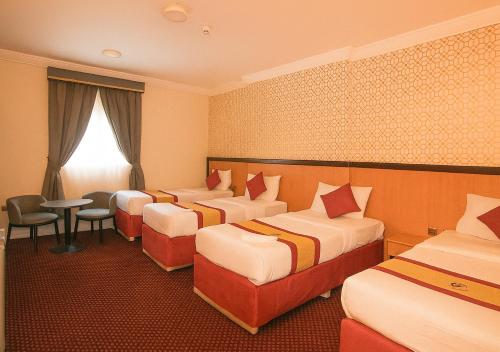 a hotel room with four beds and a table and chairs at فندق رفاق مكة in Makkah