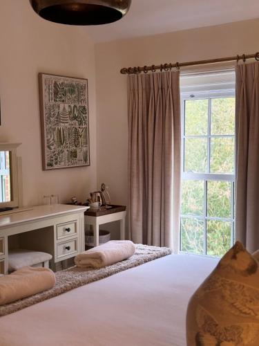 a bedroom with a bed with a desk and a window at Scarborough Hill Country Inn in North Walsham