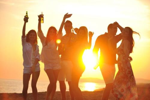 a group of people standing on the beach at sunset at Villa Freebird - Exclusive VIP Wedding & Bachelor Events in Pefkohori