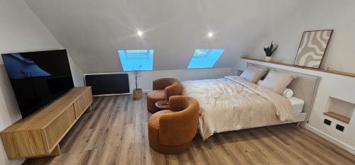 a bedroom with a bed and two chairs and a television at La suite Cherbourgeoise in Cherbourg en Cotentin