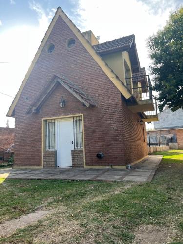 una casa in mattoni con porta bianca e balcone di La Alpina a Chivilcoy