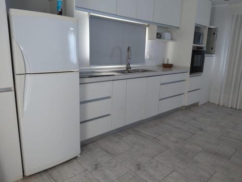 eine Küche mit weißen Schränken und einem weißen Kühlschrank in der Unterkunft Coral Sur in Mar del Plata
