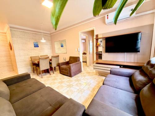 a living room with a couch and a flat screen tv at Apto 2 dorm Centro de Capão 3 quadras do Mar box e churrasqueira in Capão da Canoa