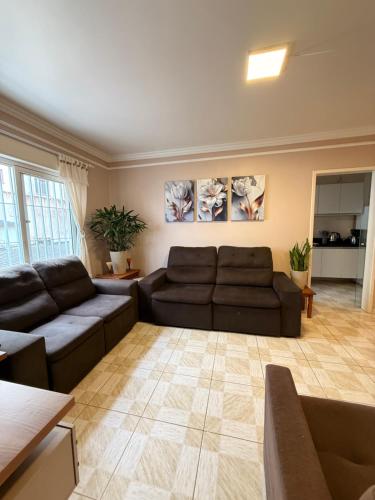 a living room with two brown couches at Apto 2 dorm Centro de Capão 3 quadras do Mar box e churrasqueira in Capão da Canoa