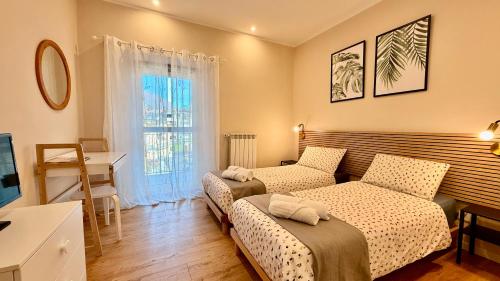 a bedroom with two beds and a desk and a window at Casa Kiara by KALMA in Domodossola