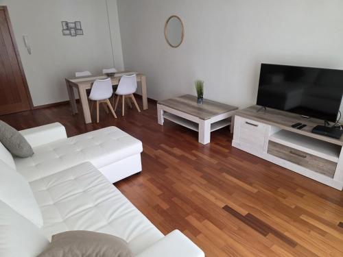 a living room with a white couch and a tv at Wings Apartment in Santa Cruz