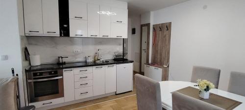 a kitchen with white cabinets and a table and a table sidx sidx sidx at Apartman Ciric in Vrnjci