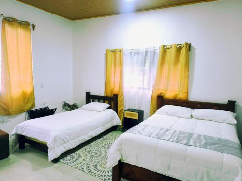 a bedroom with two beds and yellow curtains at Sloth Glamping & Villas Fortuna in San Francisco