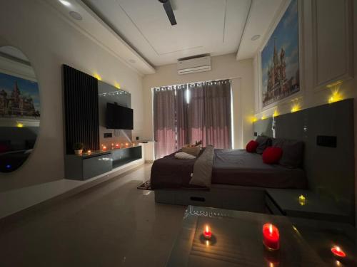 a bedroom with a bed and a television and candles at Kremlin Luxury Studios in Ghaziabad