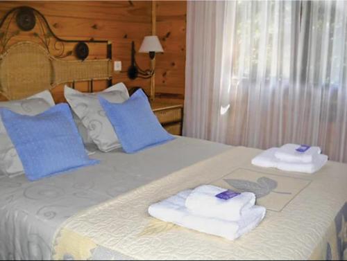 ein Bett mit blauen Kissen und Handtüchern darauf in der Unterkunft Complejo Los Abedules in La Cumbrecita