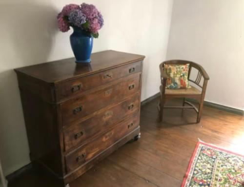 eine Kommode mit einer Blumenvase darauf und einem Stuhl in der Unterkunft Casa Fratomari - The Alpine dream in Lombro