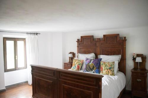 ein Schlafzimmer mit einem großen Holzbett mit Kissen in der Unterkunft Casa Fratomari - The Alpine dream in Lombro