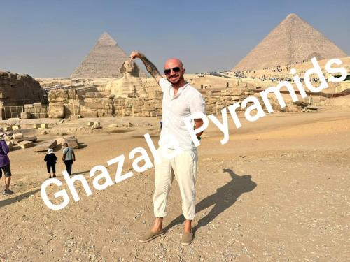 a man is standing in front of the pyramids at Ghazala Pyramids in Cairo