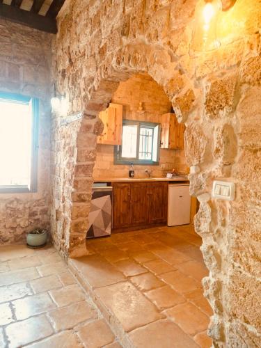 a kitchen with a stone wall and an archway at Hebi house in Acre