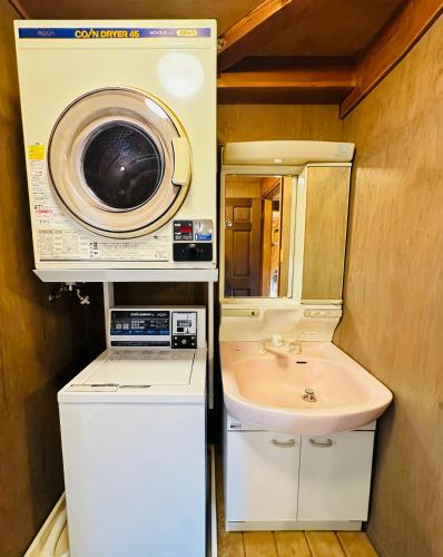 a bathroom with a washing machine and a sink at The Capsule Hakuba in Hakuba