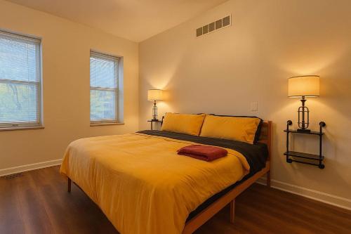 a bedroom with a bed with yellow sheets and two lamps at Soulard King Loft near Anheuser-Busch Brewery in Saint Louis