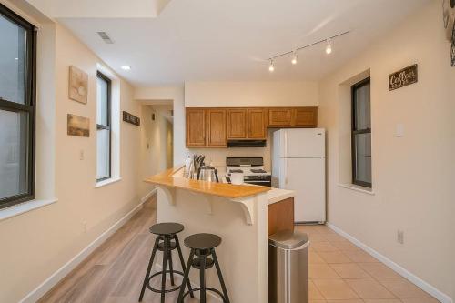 eine Küche mit einem weißen Kühlschrank und 2 Hockern in der Unterkunft Bright Soulard Loft-King-Queen 2 Baths Parking in Soulard