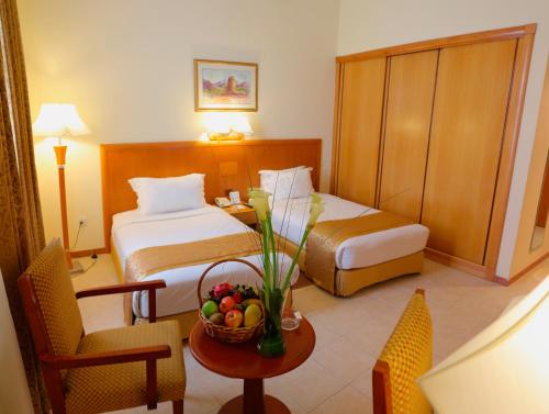 una camera d'albergo con letto e tavolo con cesto di frutta di Sharjah Premiere Hotel & Resort a Sharjah