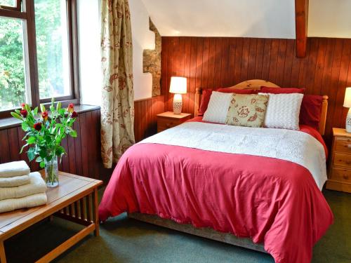 a bedroom with a red bed and a wooden wall at Cider House in Launceston