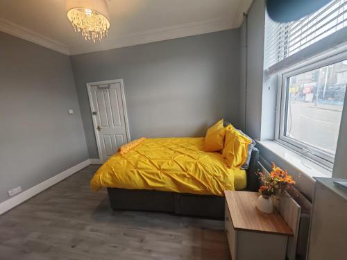 a bedroom with a bed with a yellow comforter and a window at Modern Double Rooms Near Stoke City Centre and Staffordshire Uni in Stoke on Trent