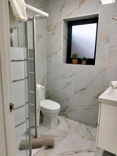 a bathroom with a toilet and a window at Costa Home in Gafanha da Nazaré
