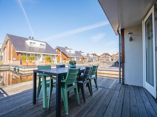 a table and chairs on a deck with a balcony at Apartment in Waterpark with Private Jetty in Uitgeest
