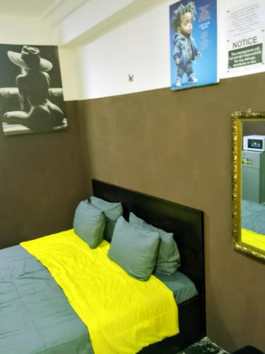 a bedroom with a bed with yellow sheets and a mirror at Short Let Apartments in Lagos Business School Lekki Ajah in Lekki