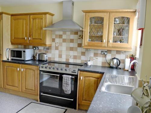 a kitchen with wooden cabinets and a stove top oven at Pipit Cottage in Burnsall