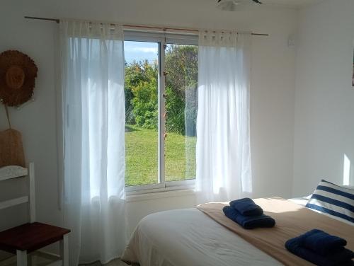 a bedroom with a bed and a window with white curtains at Casa Tiale - Chapadmalal , Campo y Olas- in Colonia Chapadmalal
