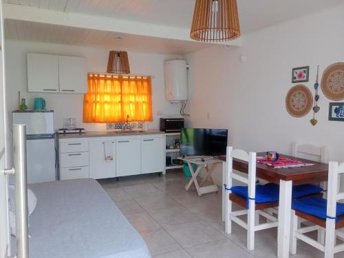 a kitchen with white cabinets and a table with chairs at Casa Tiale - Chapadmalal , Campo y Olas- in Colonia Chapadmalal