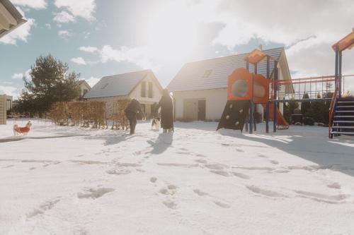 a group of people standing in the snow next to a playground at BURSZTYNOWA-PRZYSTAŃ in Lubiatowo