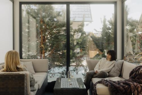 two women sitting on a couch in a living room at BURSZTYNOWA-PRZYSTAŃ in Lubiatowo