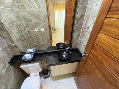 ein Badezimmer mit Toilette, Waschbecken und Spiegel in der Unterkunft Casa com 2 suites em condomínio no Frances in Marechal Deodoro