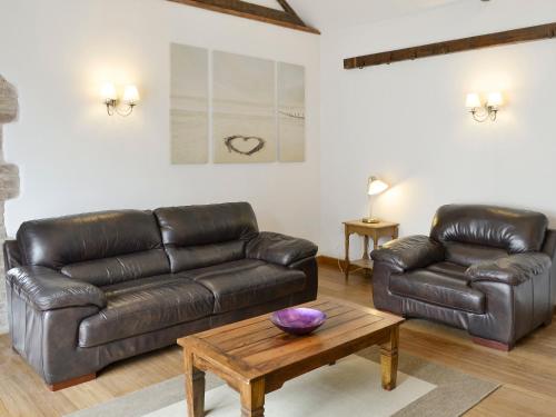 a living room with a leather couch and a coffee table at The Coach House in Whittingham